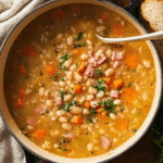 Cozy navy bean soup recipe with ham and vegetables in a warm rustic bowl.