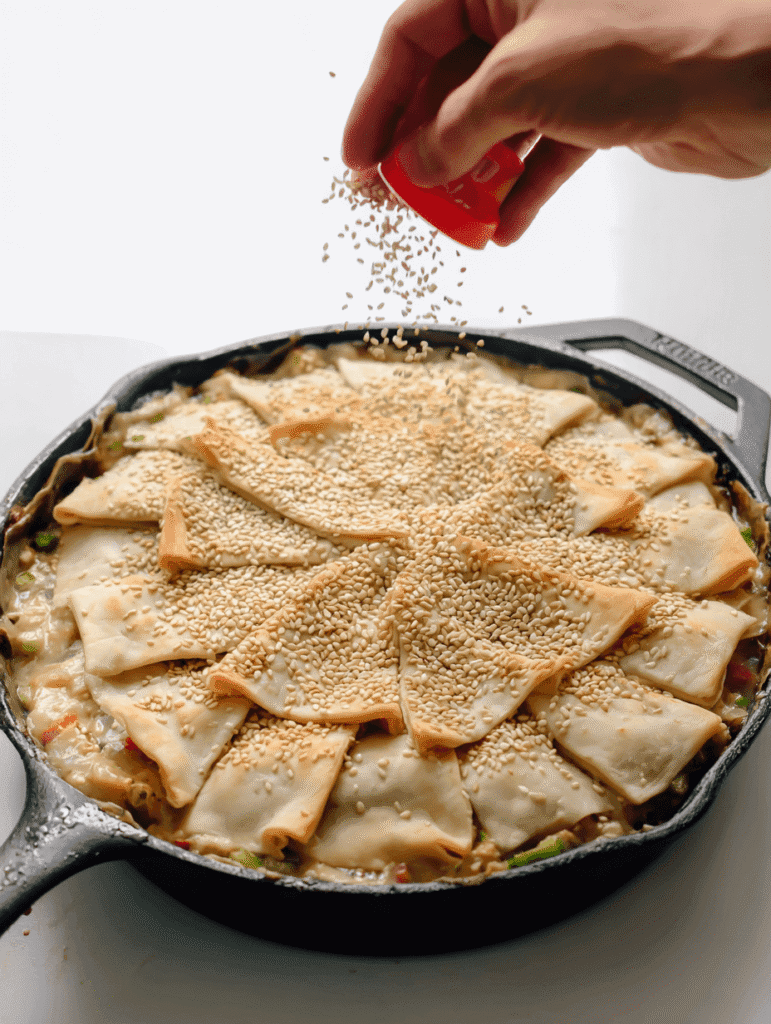 unbaked chicken pot pie crust topped with sesame seeds