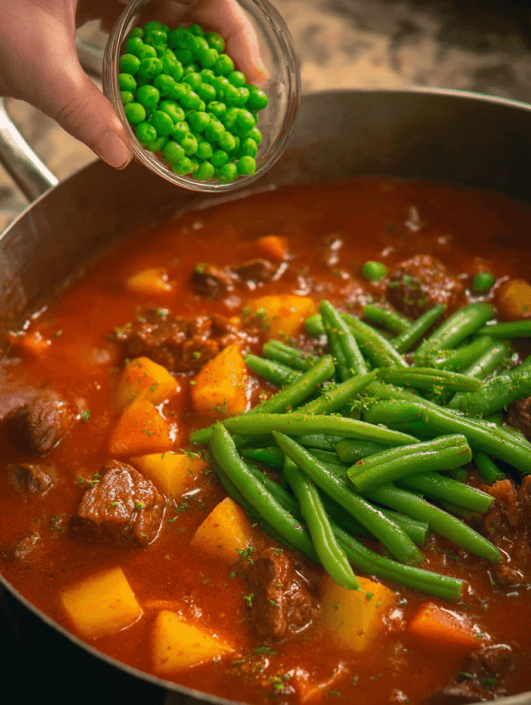 Adding peas and green beans to simmering Old Fashioned Vegetable Beef Soup