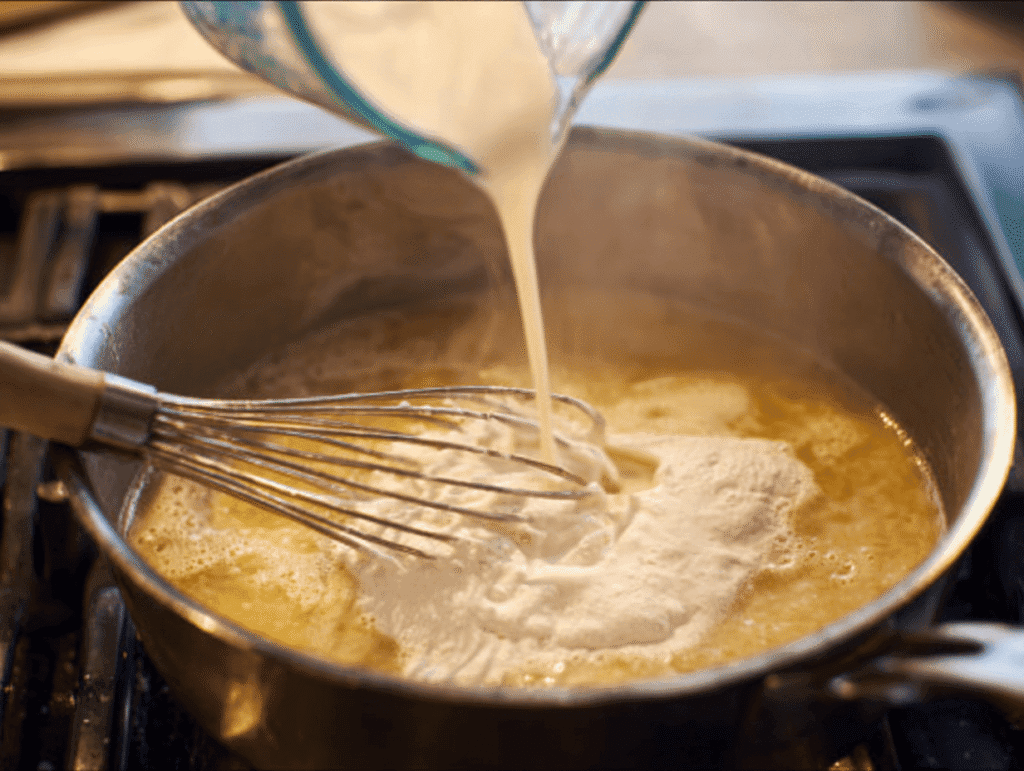 whisking cream into flour and butter to make creamy base for chicken and wild rice soup recipe
