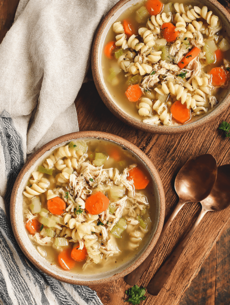 High Protein Chicken Noodle Soup – The Ultimate Cozy 30-Minute Meal 2 Two bowls of High Protein Chicken Noodle Soup with curly chickpea noodles, carrots, celery, and shredded chicken.