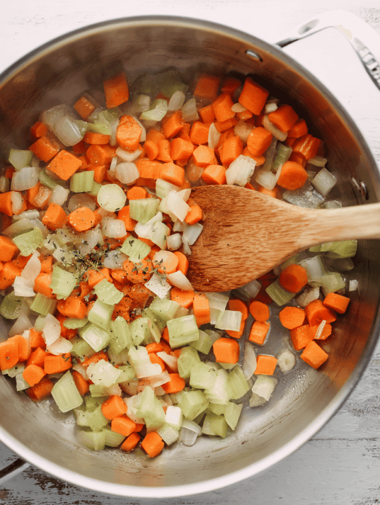 High Protein Chicken Noodle Soup – The Ultimate Cozy 30-Minute Meal 4 Carrots, celery, and onions sautéing in a pot for High Protein Chicken Noodle Soup.