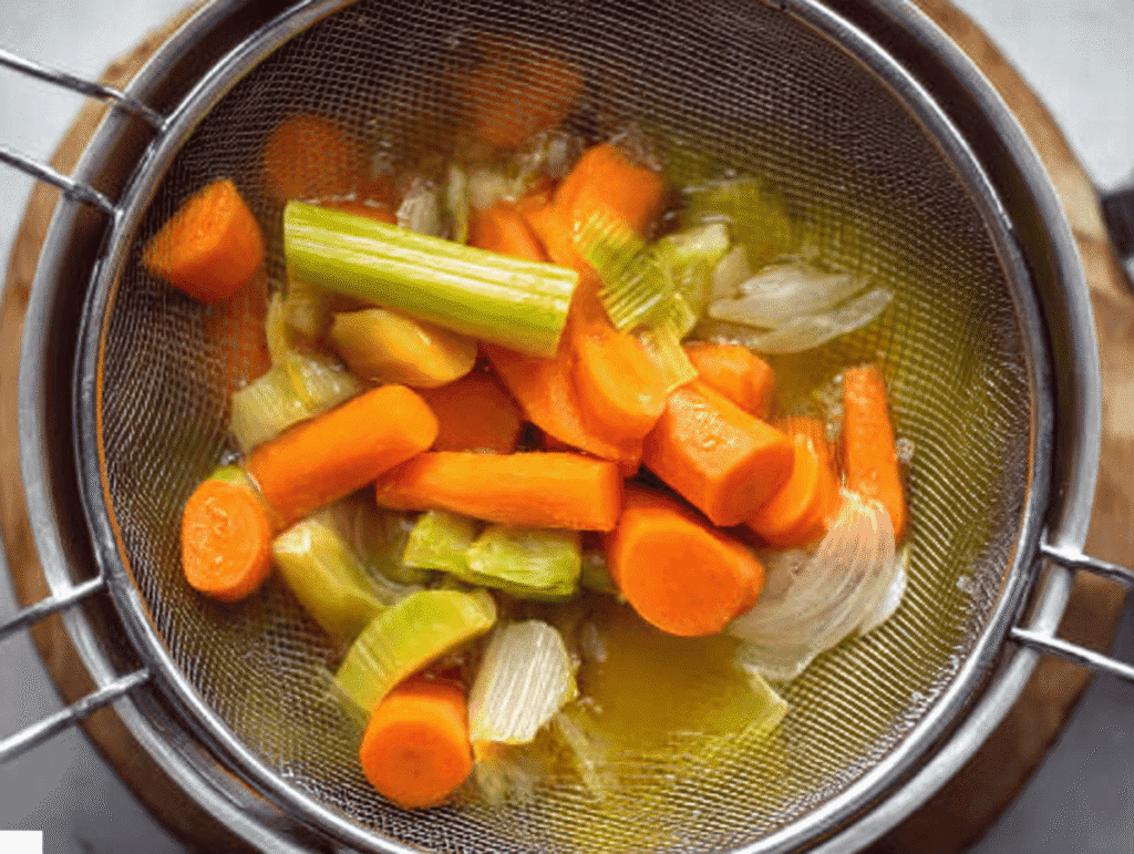 Straining cooked carrots, celery, and onions from broth for Italian Penicillin Soup Recipe