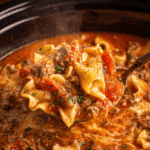 Ladle serving lasagna soup crockpot with noodles, beef, and melted cheese
