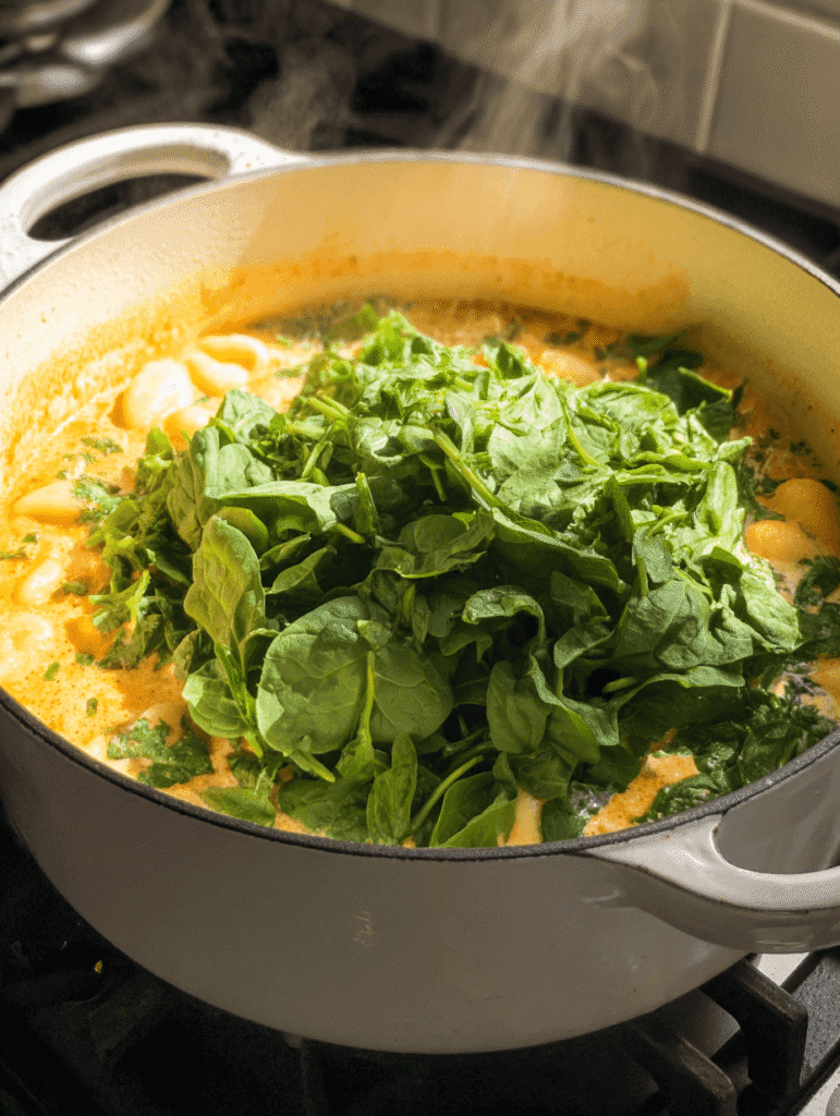 Adding fresh spinach to creamy Marry Me Chicken Gnocchi Soup