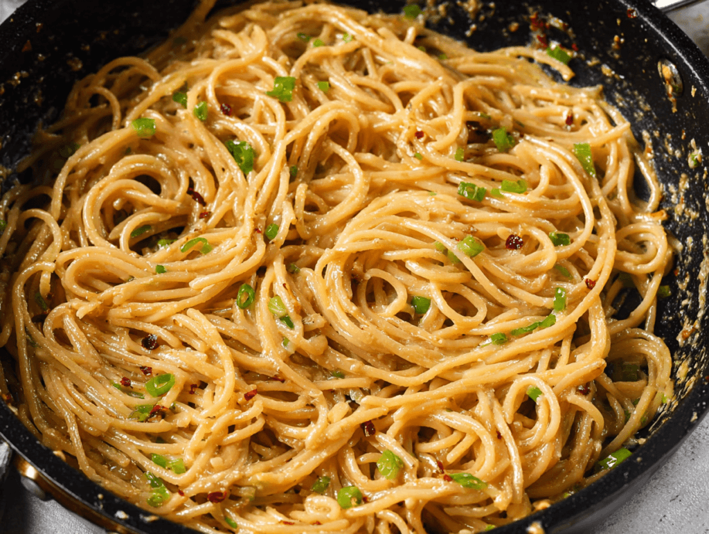 Creamy vegan garlic noodles tossed in a skillet with green onions and chili flakes